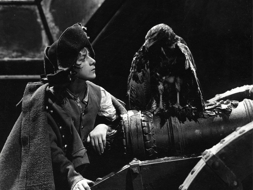 still from Napoleon (1927) - a black and white image of napoleon as a child in military dress leaning against a cannon looking into the eyes of an eagle